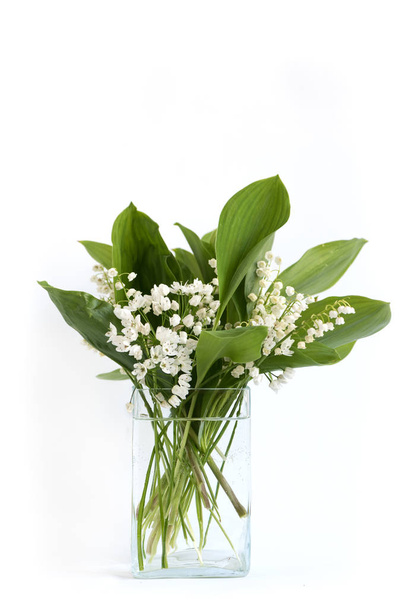 Lily of the valley flowers in glass vase, black background, selective focus - Foto, imagen