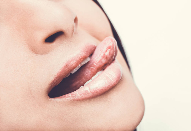 Beautiful woman leaking teeth with tongue close up. - Фото, изображение