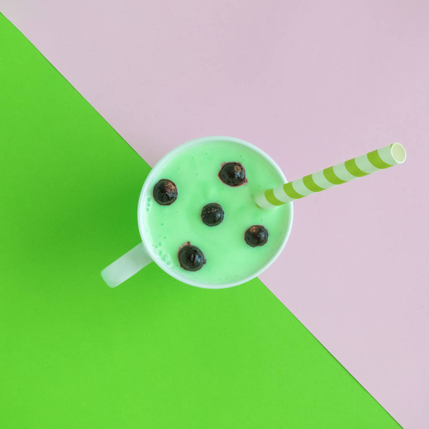 High angle view of cup of blueberries smoothie on green and pink background. - Photo, image