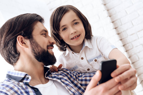 Happy father and son use smartphone at domestic. - Фото, изображение