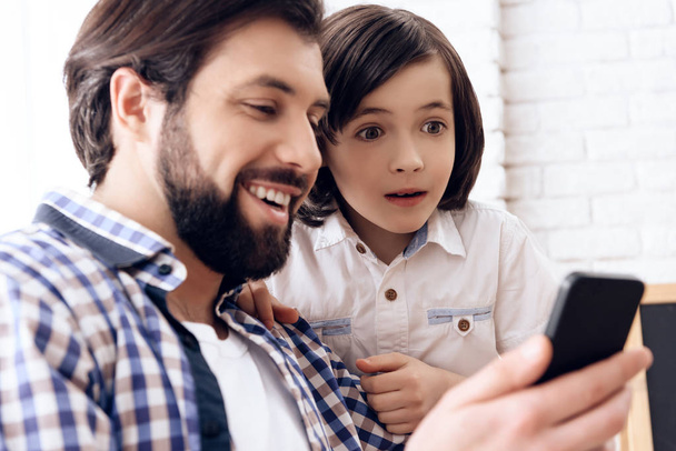 Happy father and son use smartphone at domestic. - Фото, изображение