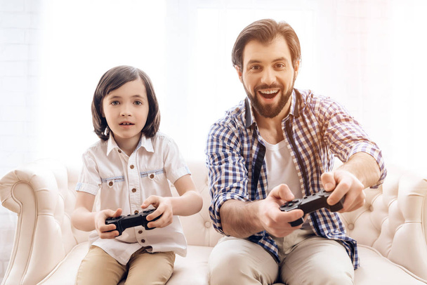 Bearded father with son plays computer game using game controllers. - Foto, afbeelding