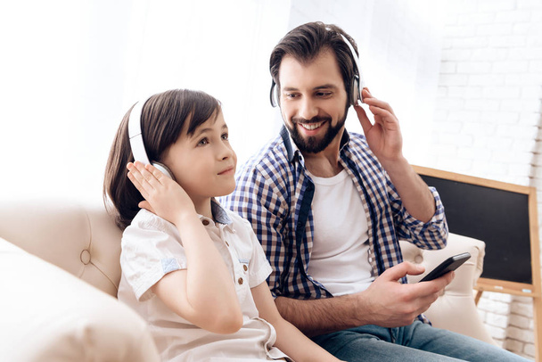 Bearded father and small son in headphones listen to music from smartphone. - Photo, Image