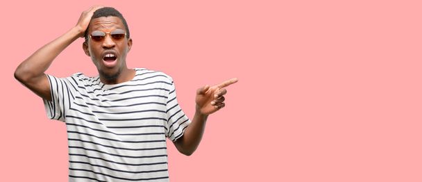 Africano nero uomo indossare occhiali da sole che punta via lato con dito
 - Foto, immagini