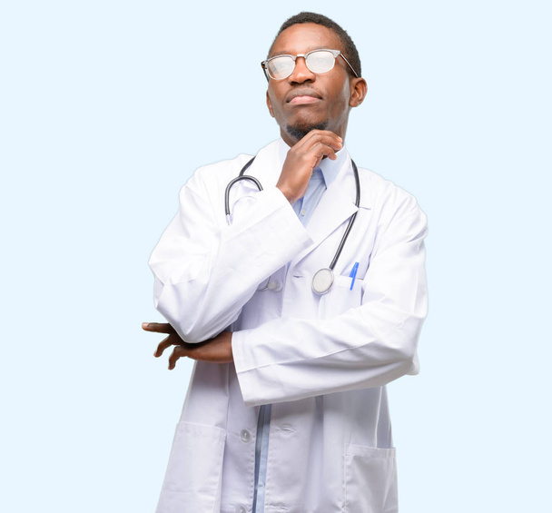 Joven médico negro, profesional médico pensando y mirando hacia arriba expresando dudas y maravillas
 - Foto, imagen