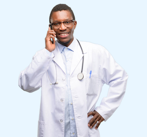 Jonge zwarte dokter, medische professional gelukkig praten via gsm smartphone - Foto, afbeelding