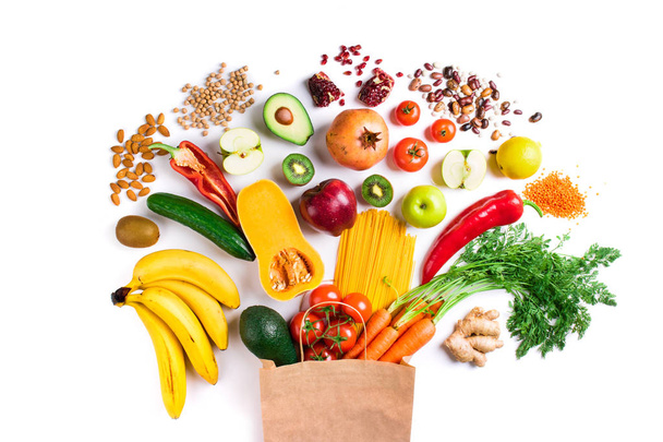 Zdravé potraviny na pozadí. Zdravé vegetariánské jídlo v papírové sáčku těstovin, zeleniny a ovoce na bílém pohled shora. Nakupování jídla - Fotografie, Obrázek