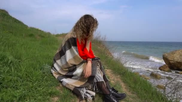 Счастливая молодая женщина в красном платье, завернутая в ковёр, весело провела время у скалы на берегу моря
 - Кадры, видео