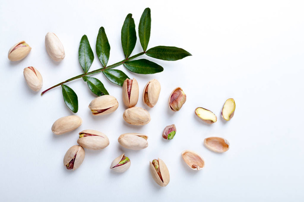 Pistachios with leaves on white background, top view - Foto, Imagen