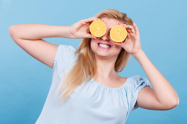 Girl covering her eyes with lemon citrus fruit - Фото, изображение