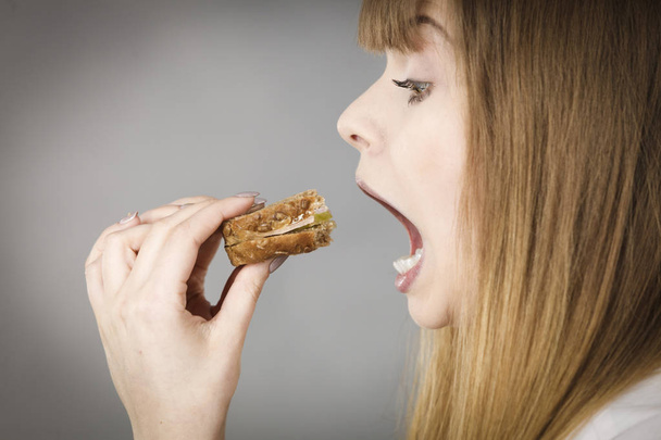 Жінка їсть сендвіч, кусаючи
 - Фото, зображення
