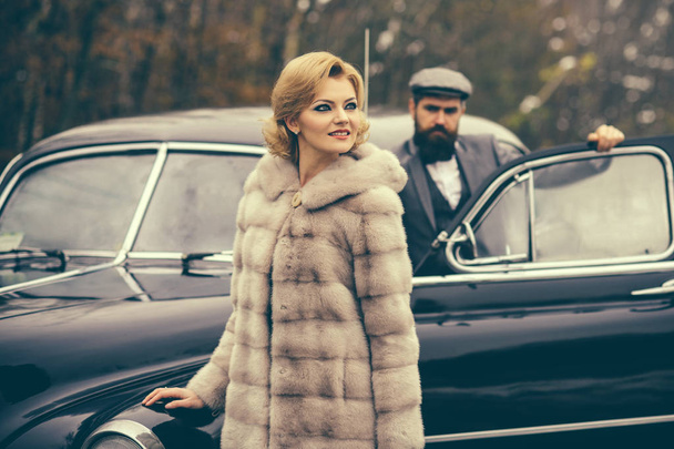 Travel and business trip or hitch hiking. Bearded man and sexy woman in fur coat. Retro collection car and auto repair by mechanic driver. Couple in love on romantic date. Escort of girl by security. - Fotografie, Obrázek