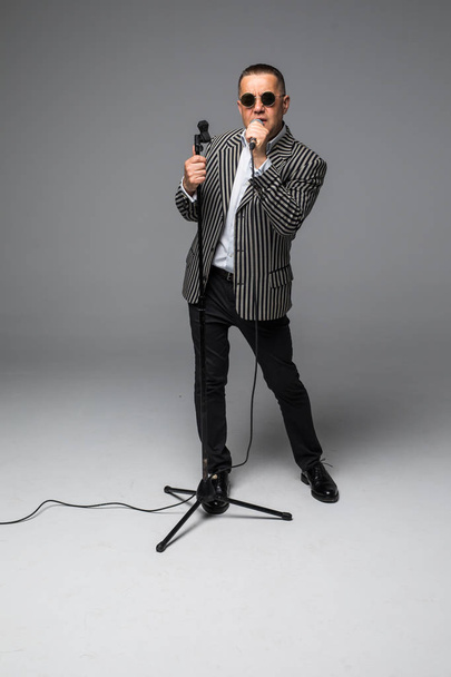 Інтерв'юер шоумена середнього віку з емоціями. Молодий елегантний зрілий чоловік тримає мікрофон на білому тлі. концепція Showman
. - Фото, зображення