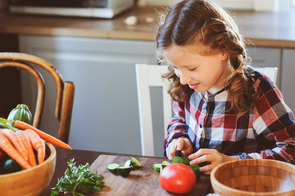 child girl helps mom to cook and cut fresh vegetables for salad with knife. Kids learning house work on farm on summer vacations - Photo, image