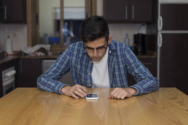 adulto joven con teléfono móvil en la cocina casera
 - Foto, imagen