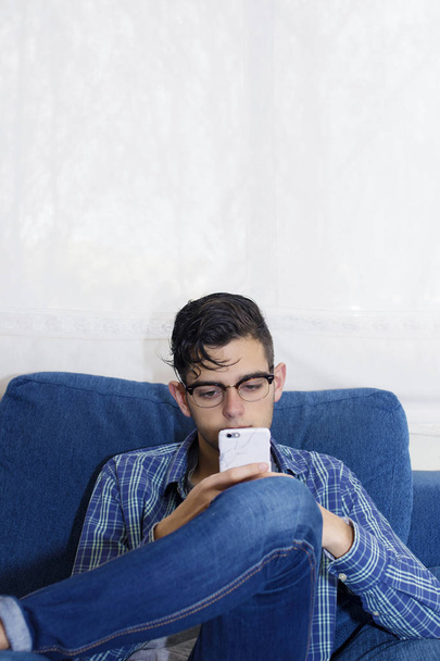 young casual in the home sofa with mobile phone - Photo, Image