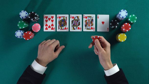Lucky man has royal flush hand, wins much money in poker game, enjoying success - Foto, afbeelding