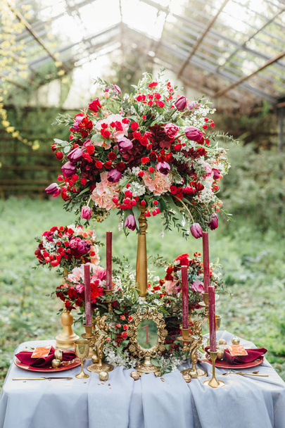 крупным планом фотография красивого свадебного декора с красными цветами и свечами на открытом столе
 - Фото, изображение