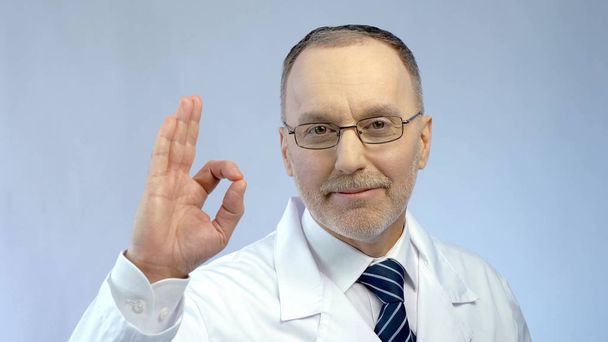 Medico maschio sorridente, mostrando gesto OK, sicuro dei risultati del trattamento di successo
 - Foto, immagini