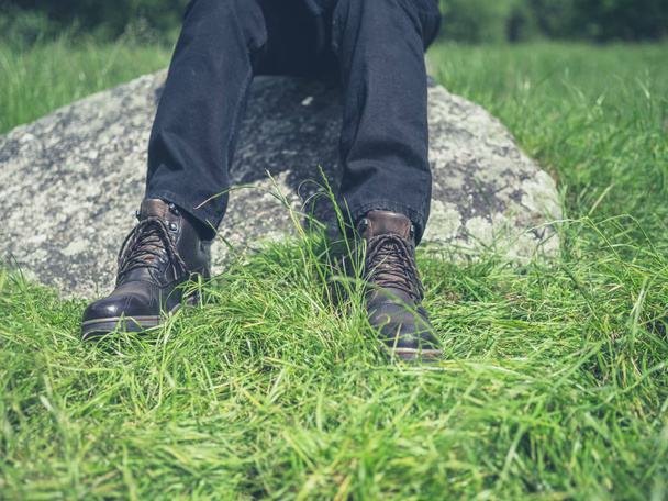 Os pés de um homem sentado em uma rocha na natureza
 - Foto, Imagem
