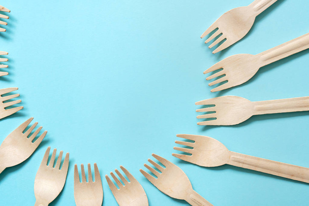 wooden forks lie in a circle on a blue background - Photo, Image