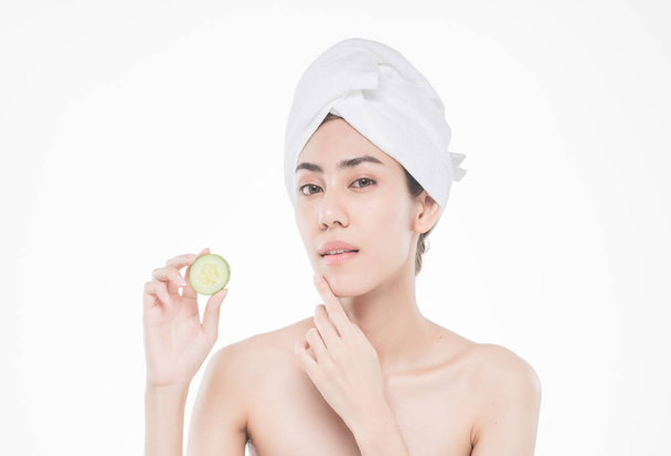 beautiful asia woman with towel on head with perfect clean skin smiling holding cucumber slices over white background. Beauty cosmetology and spa. - Photo, Image