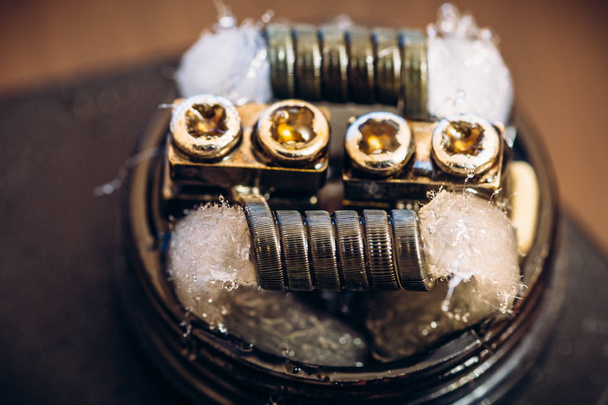 atomizador de goteo reconstruible o RDA para vapear o cigarrillos electrónicos con bobina Alien Clapton y rayas de algodón mojadas con e-líquido
 - Foto, imagen