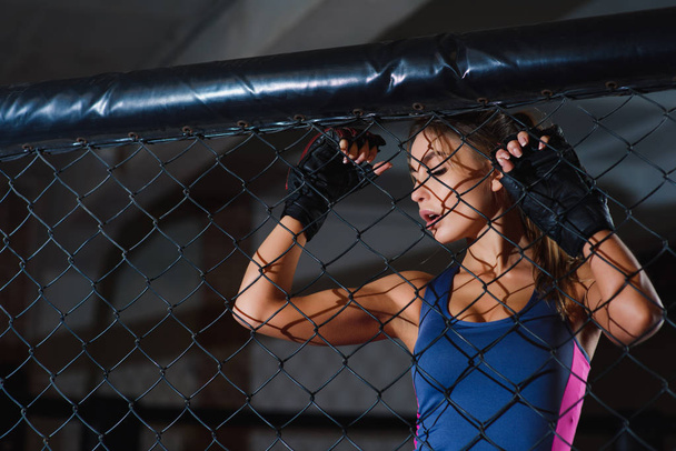 Сексуальная женщина позирует рядом с сеткой боксерского ринга
 - Фото, изображение
