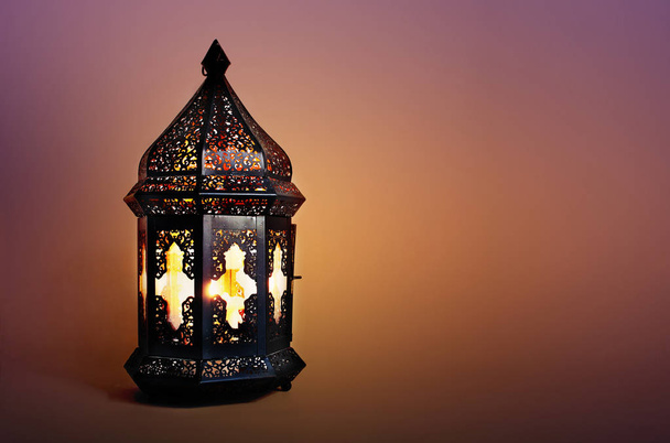 Ornamental dark Moroccan, Arabic lantern on the table. Burning candle in the night. Greeting card for Muslim community holy month Ramadan Kareem. Festive blurred background. - Фото, зображення