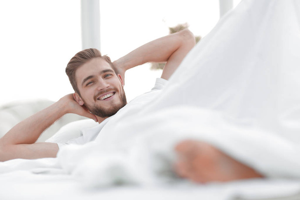 closeup.smiling man resting in the bedroom - Фото, изображение