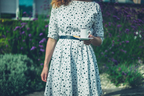 Young woman with cup of coffee in garden  - Valokuva, kuva