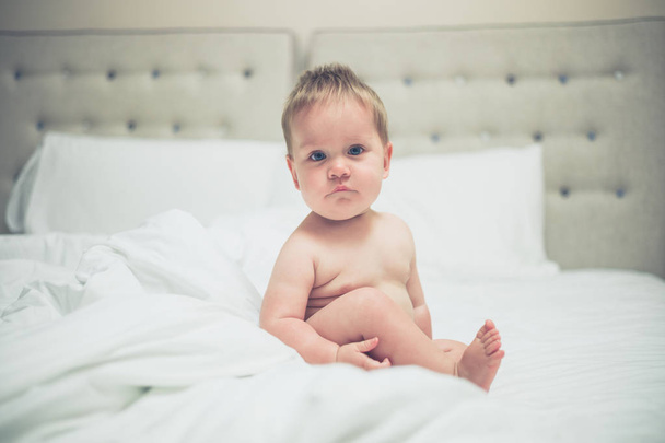Cute little baby sitting on bed in the morning - Foto, afbeelding