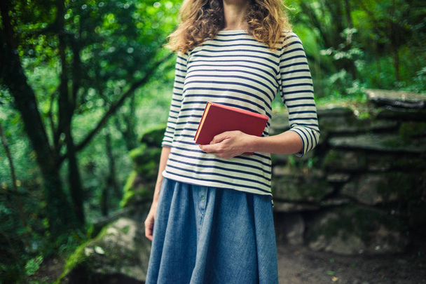 Woman with book standing in the forest - Фото, зображення