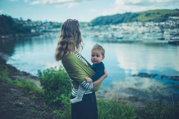 Young mother with baby by seaside village - 写真・画像