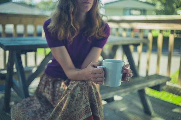 Mujer bebiendo de la taza en el parque de remolques
 - Foto, imagen