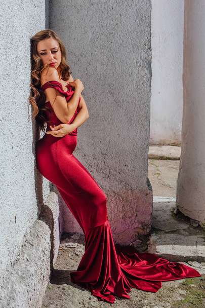Beautiful young woman in a long red evening gown with a train - Fotoğraf, Görsel