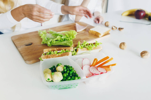 Boîtes à lunch scolaires avec sandwichs et légumes frais, bouteille d'eau sur la table de cuisine maison
 - Photo, image