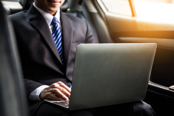 Handsome Young businessman using laptop and sitting in back seat - Zdjęcie, obraz