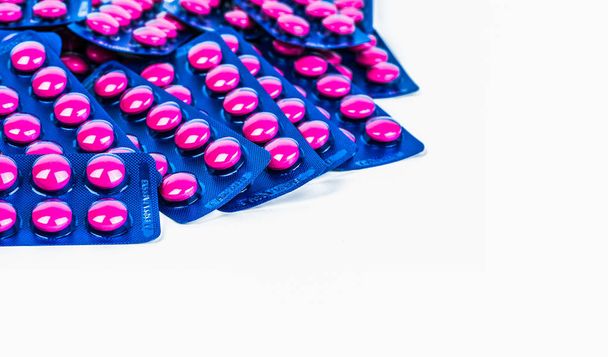 Ибупрофен в розовых таблетках таблетки упакованы в синий пузырь пакет изолированы на белом фоне с копированием пространства. Ибупрофен для облегчения боли, головной боли, высокой температуры и противовоспалительных. Таблетки для обезболивающих
.  - Фото, изображение