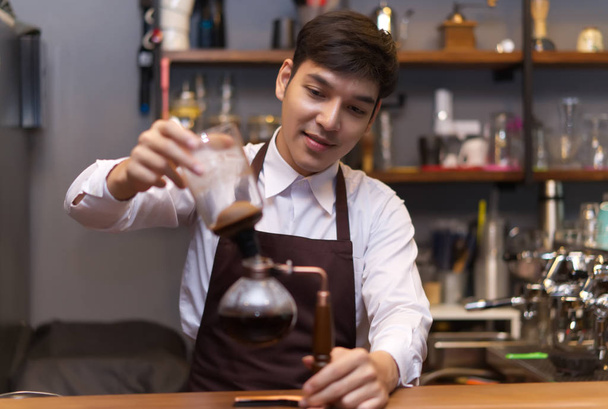 Jonge Aziatische knappe Kaukasische barista koffie met Sipho gieten - Foto, afbeelding