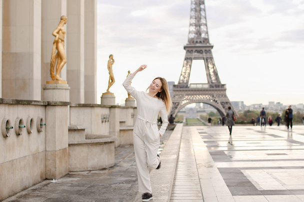 Mukava nainen kävelee Trocadero aukiolla lähellä kullattuja patsaita ja Eiffel-torni
. - Valokuva, kuva