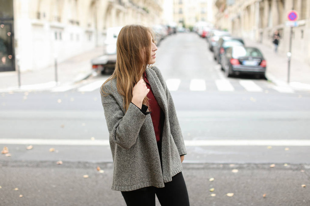 Young blonde woman walking in city on street and wearing jacket. - Fotoğraf, Görsel