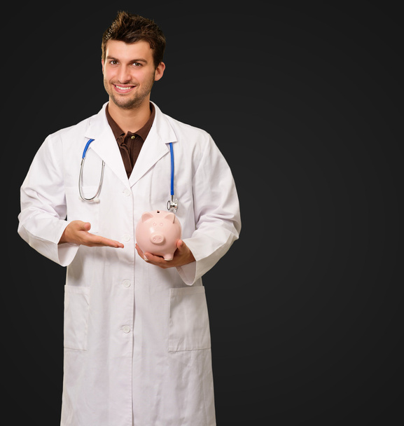 Young Doctor Holding Piggy Bank - Foto, Bild