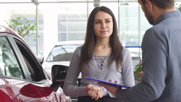 Mujer joven hablando con el vendedor en el concesionario de automóviles
 - Metraje, vídeo
