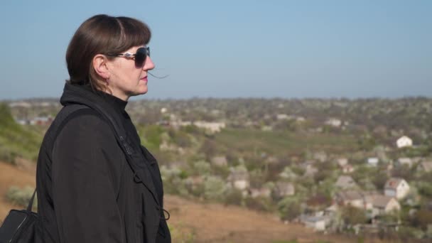 Portret van een jonge vrouw tegen een achtergrond van gebouwen onscherp - Video