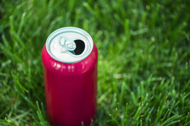 close up vista de refrigerante em lata rosa no gramado verde
 - Foto, Imagem