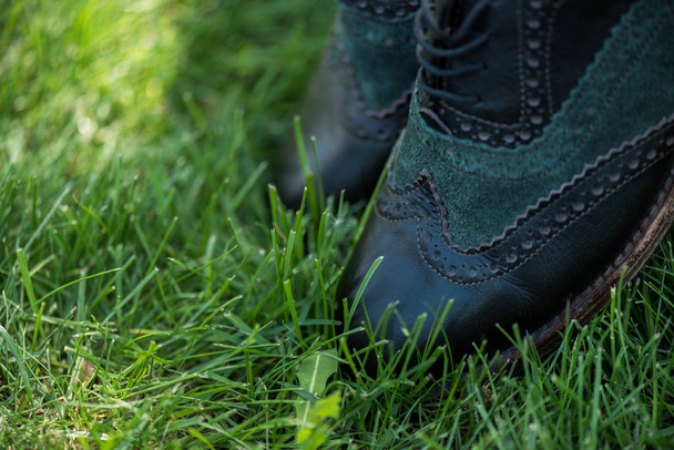 selective focus of black leather shoes on green grass - Foto, imagen