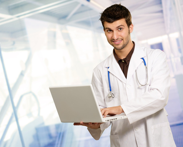 Молодой врач держит ноутбук
 - Фото, изображение