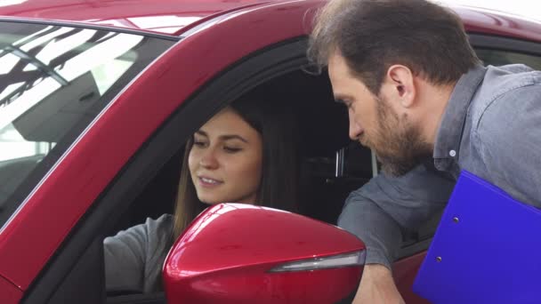 attraktive Frau sitzt in einem neuen Auto und spricht mit dem Verkäufer - Filmmaterial, Video