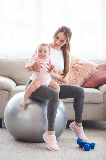 Young pretty mother working out with her little child at home - Fotoğraf, Görsel
